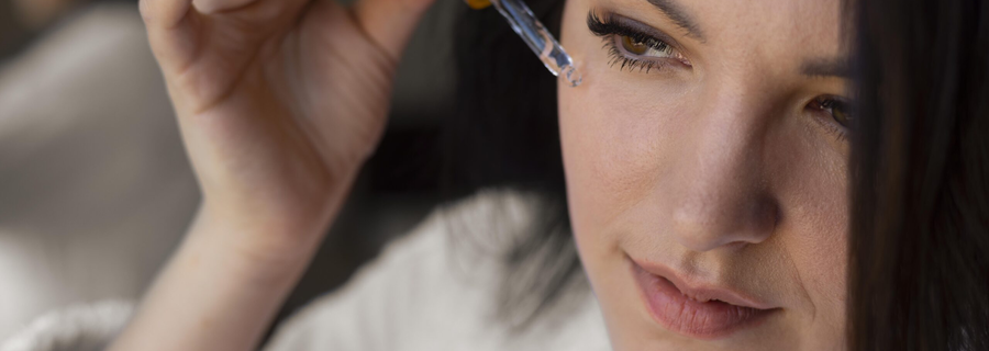 A beautiful woman applying vitamen C serum on her face.