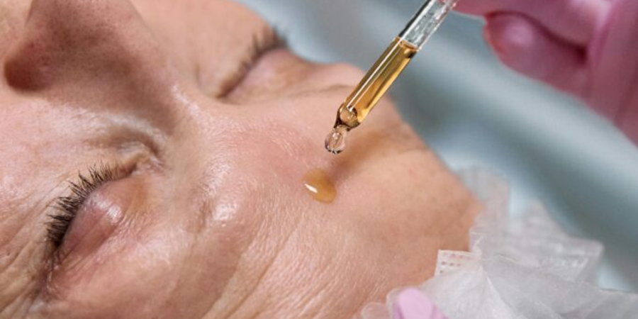 vitamin C serumis being applied on elderly woman face.