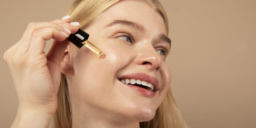 A young women apply vitamin C serum on her face with big smile.