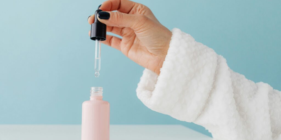 A woman hand is taking out vitamin c serum from bottle.