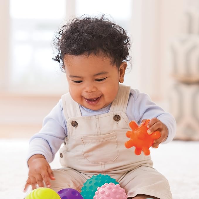 An infant is playingwith Infantino Textured Multi ball set with the huge and wide smile on his face.Best sensory toy for the development of babies and toddlers sense of touch.